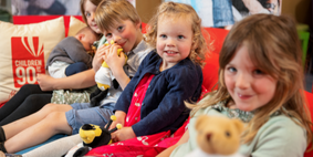 5 children sat on a red sofa